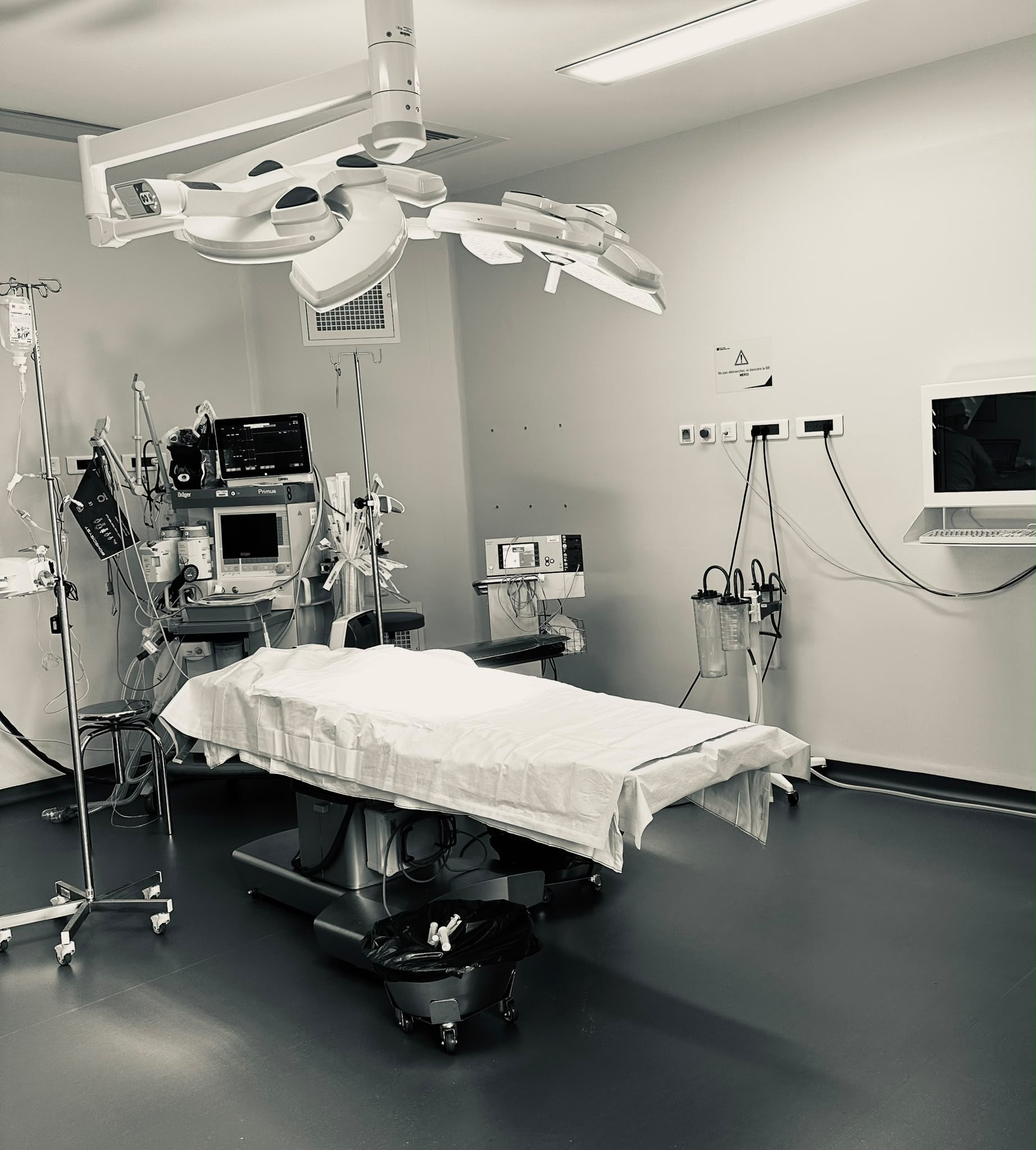 Salle d'intervention entièrement équipée et prête à accueillir un patient — table, scialytiques, station d'anesthésie et moniteurs